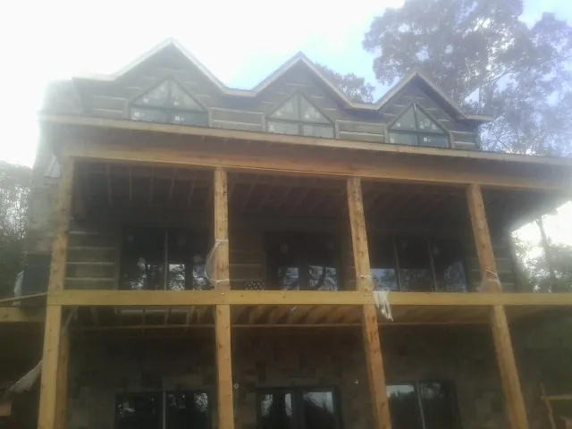 Dormers and porch framing on a large log home under construction — Roof Coating work by our crew in Westbrook